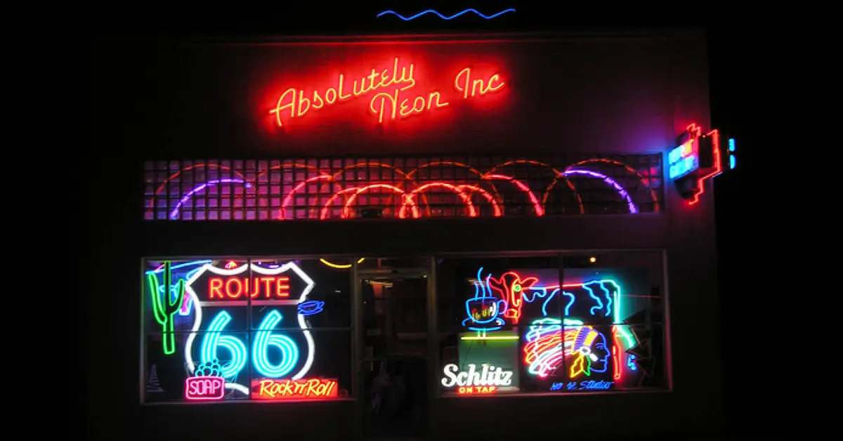 Storefront displaying colorful neon signs, including Route 66 and Absolutely Neon.